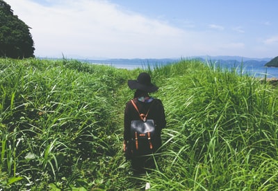 女人站在绿草中间附近海在白天
